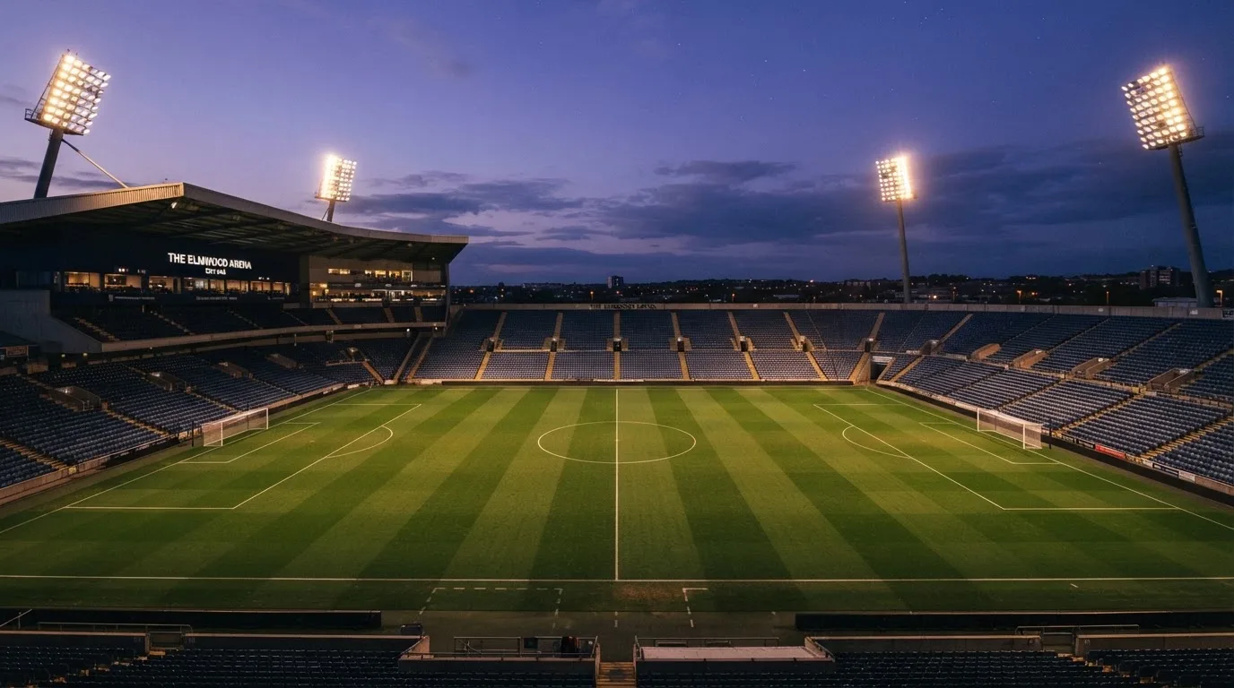 An empty football stadium with floodlight masts at dusk