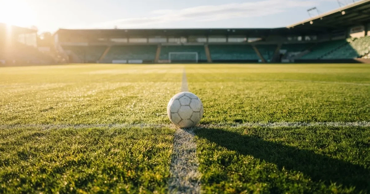 A ball on the centre spot of a grass pitch in morning light