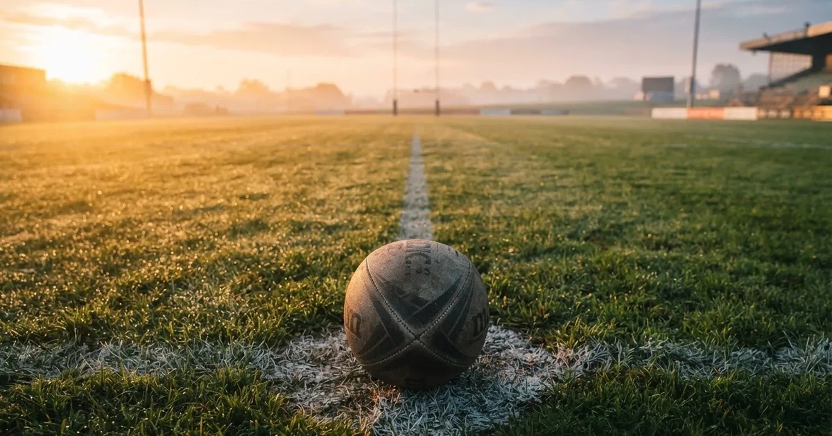 A ball on the centre spot of a grass pitch in morning light