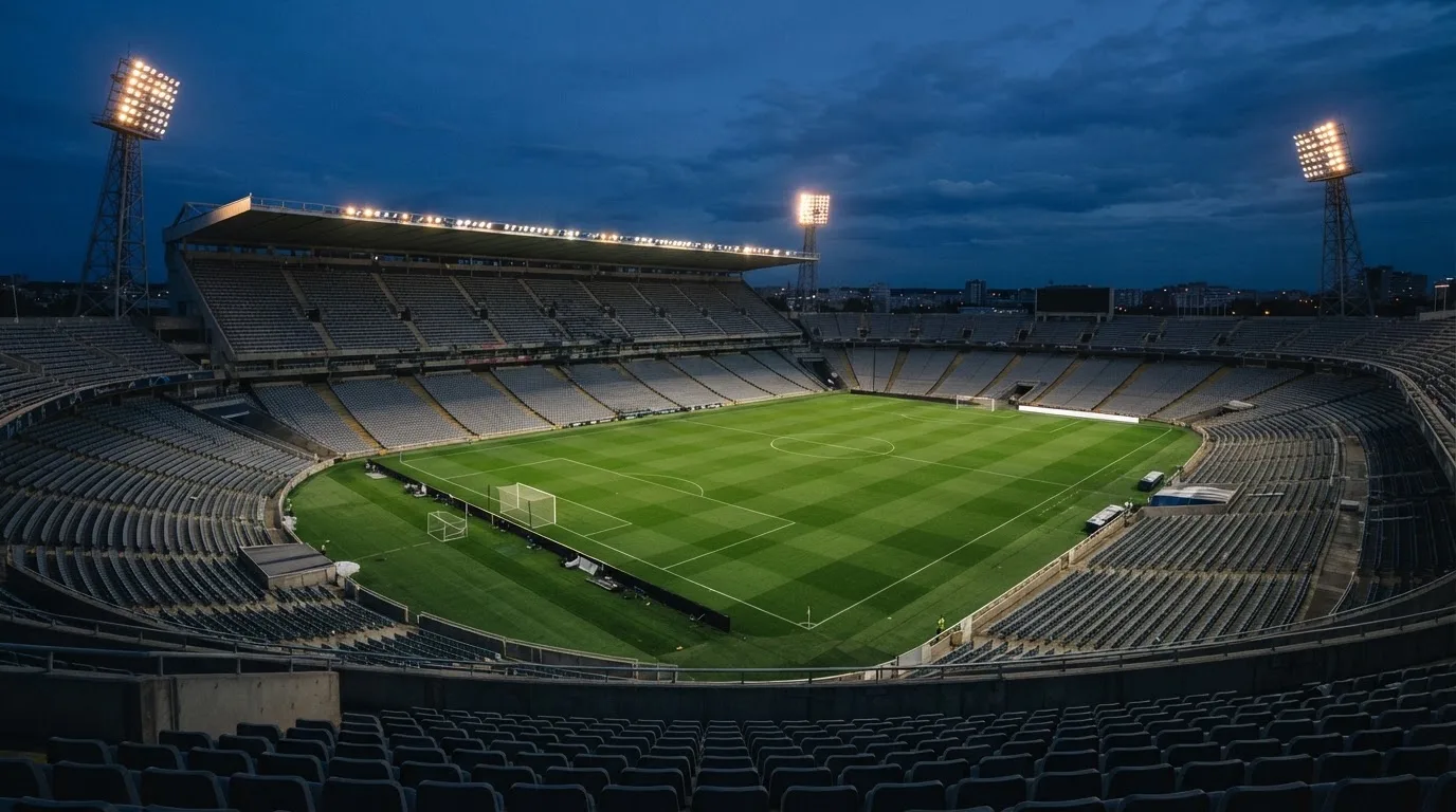 An empty football stadium with floodlight masts at dusk