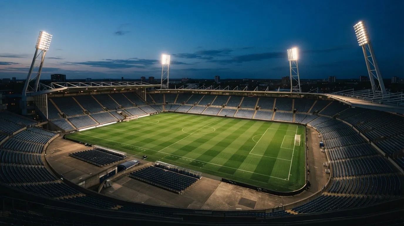 An empty football stadium with floodlight masts at dusk