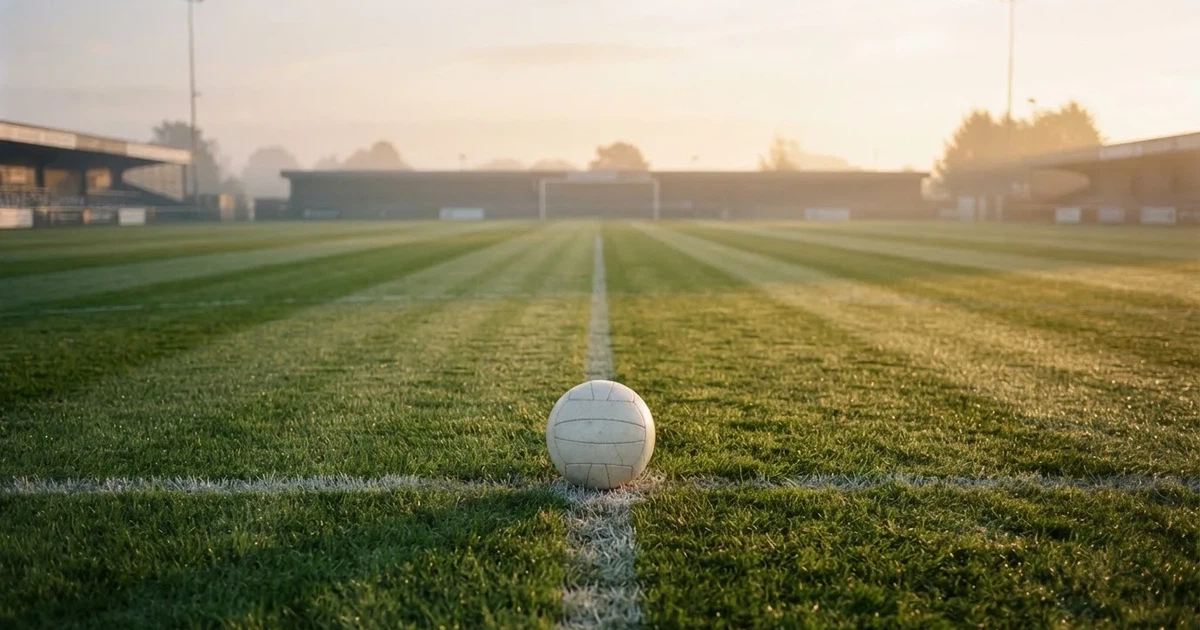 A ball on the centre spot of a grass pitch in morning light