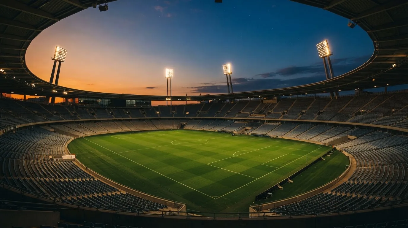 An empty football stadium with floodlight masts at dusk