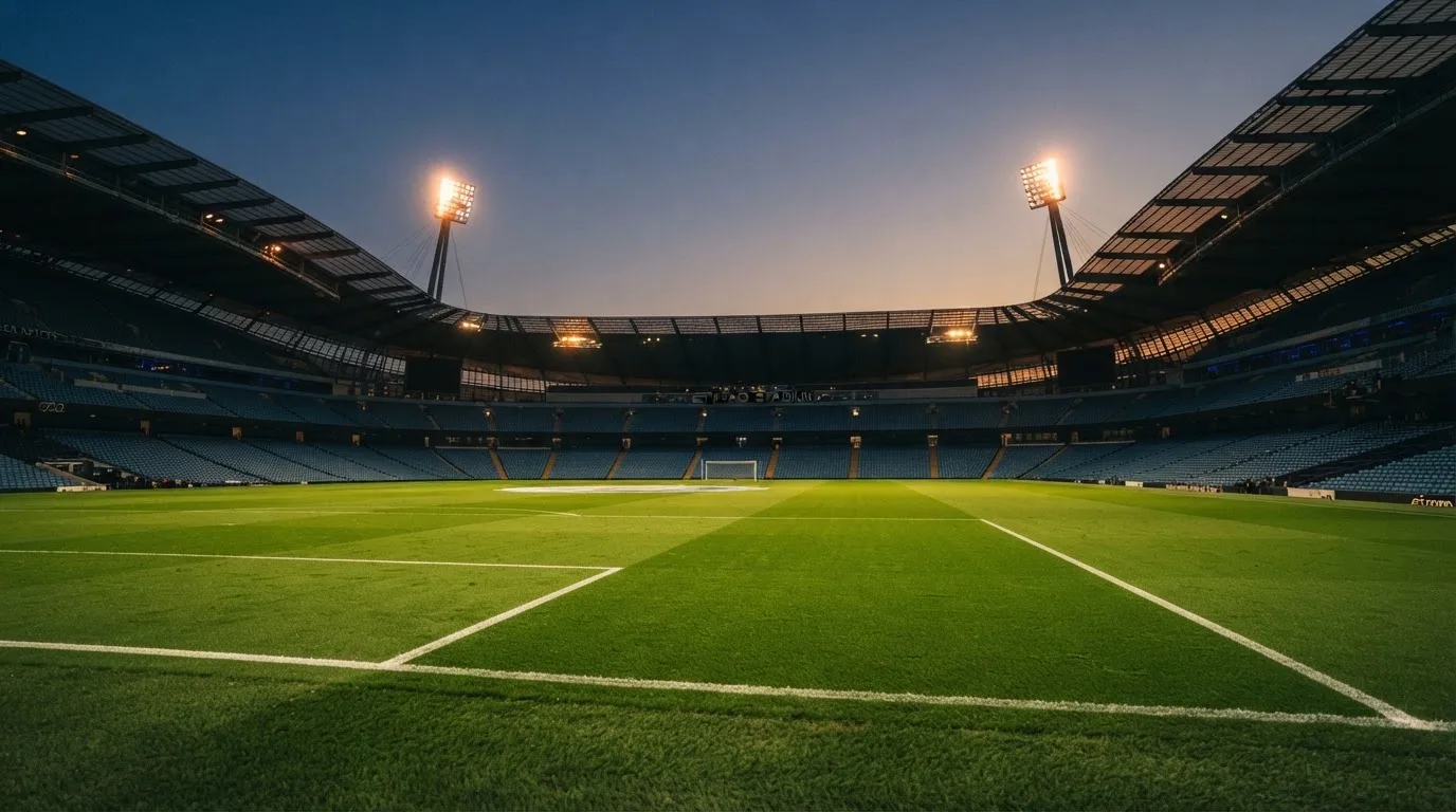 An empty football stadium with floodlight masts at dusk