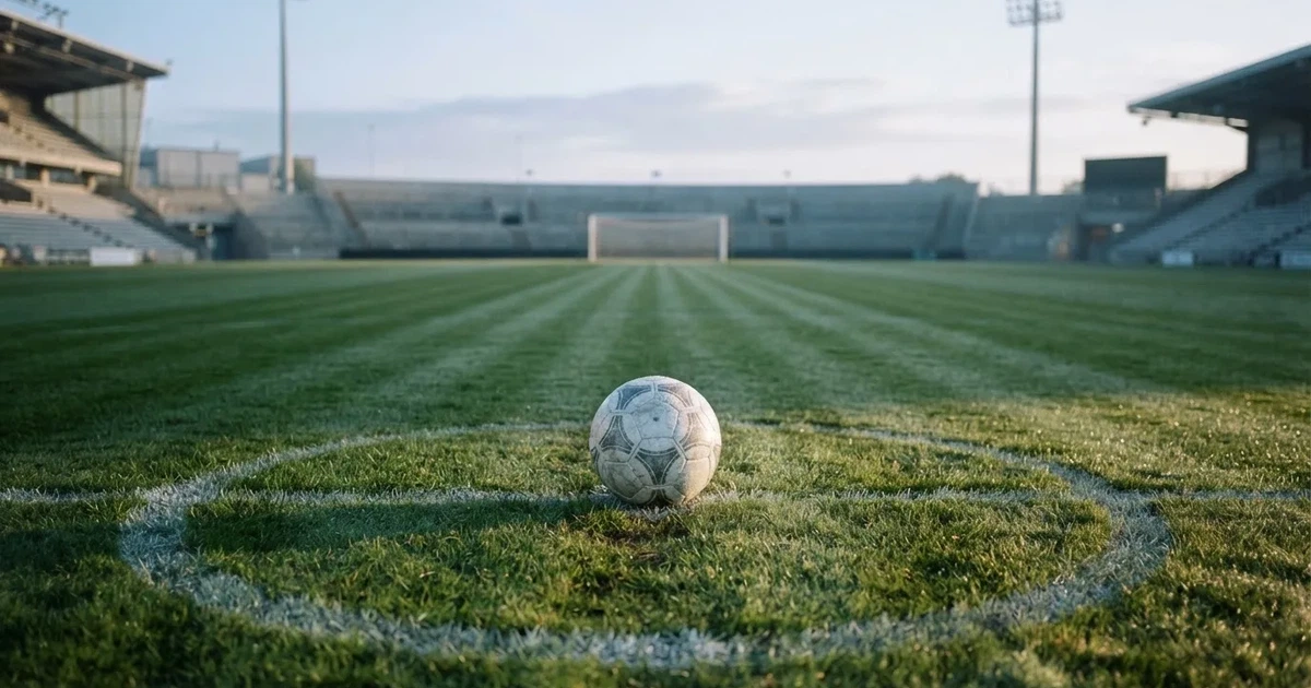 A ball on the centre spot of a grass pitch in morning light