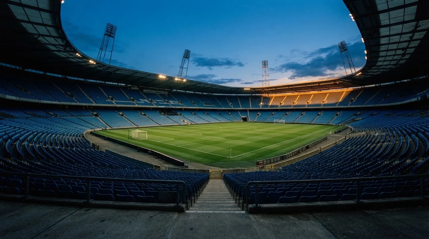 An empty football stadium with floodlight masts at dusk