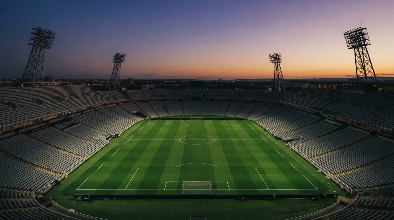 An empty football stadium with floodlight masts at dusk